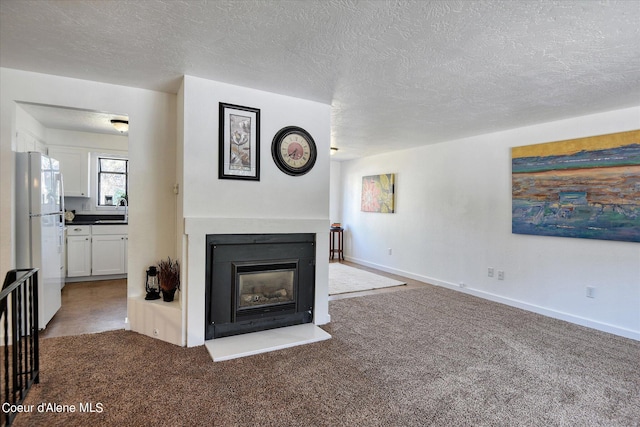 carpeted living room featuring a textured ceiling and sink