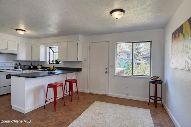 kitchen featuring white electric range oven, a textured ceiling, white cabinets, and a healthy amount of sunlight