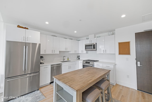 kitchen featuring white cabinets, appliances with stainless steel finishes, light wood-type flooring, and sink