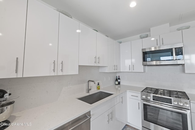 kitchen featuring light stone counters, sink, white cabinets, and stainless steel appliances