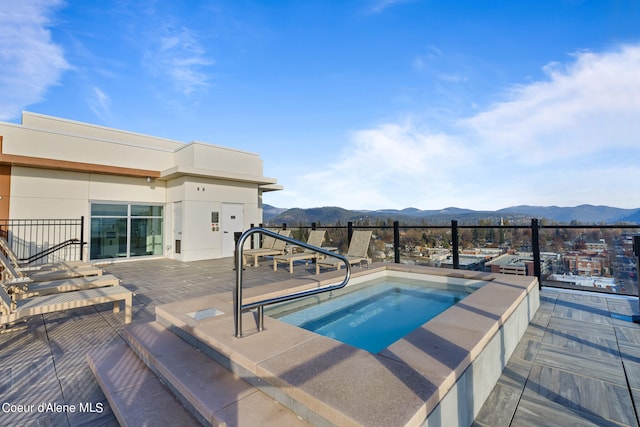 view of swimming pool featuring a patio area, a mountain view, and an in ground hot tub