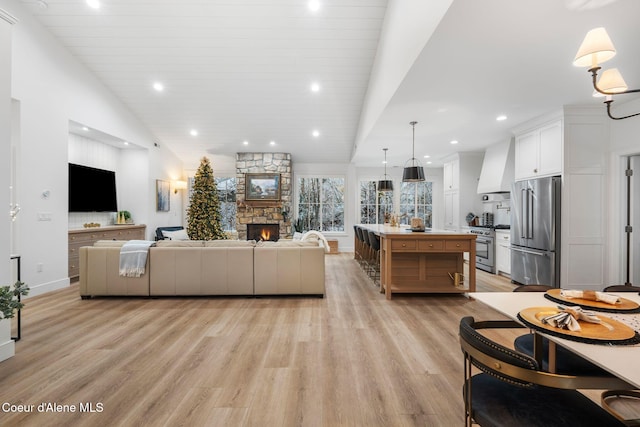 living room featuring high vaulted ceiling, light wood-type flooring, a fireplace, and wood ceiling