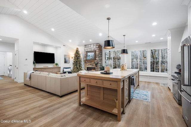 kitchen with white cabinetry, pendant lighting, a fireplace, a kitchen island, and light wood-type flooring