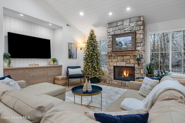 living room with a stone fireplace and lofted ceiling