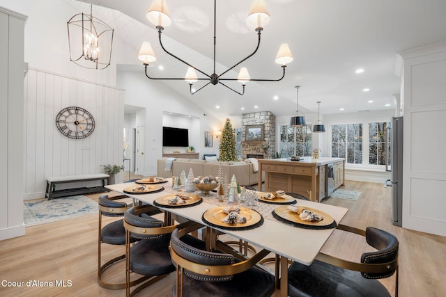 dining area with a chandelier, high vaulted ceiling, and light hardwood / wood-style flooring