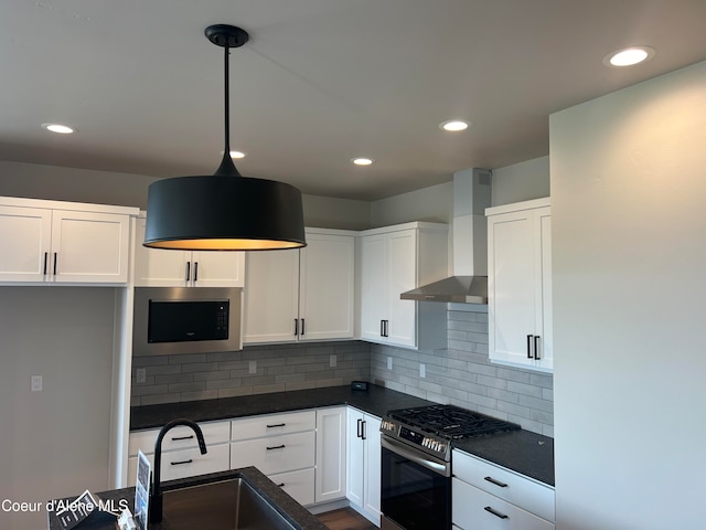 kitchen with sink, hanging light fixtures, wall chimney exhaust hood, white cabinetry, and stainless steel appliances