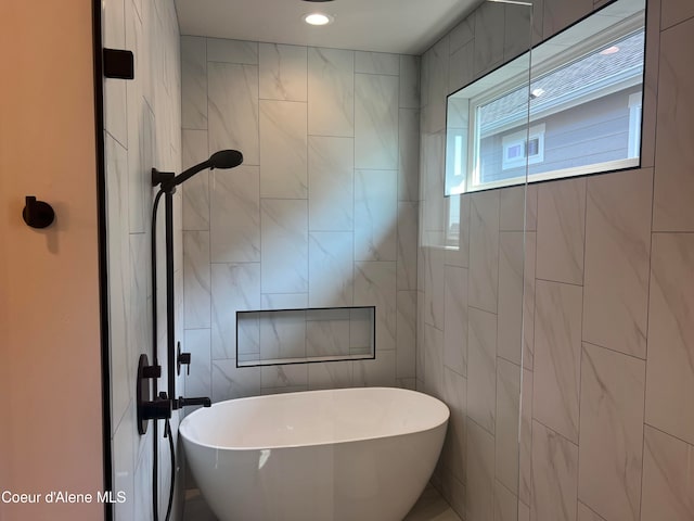 bathroom featuring a tub to relax in and tile walls