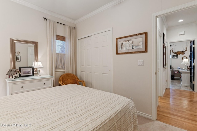 bedroom with a closet, ornamental molding, and light wood-type flooring