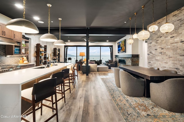 dining room featuring a glass covered fireplace, brick wall, and light wood finished floors