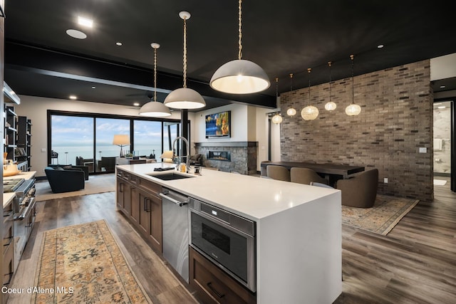 kitchen with a glass covered fireplace, open floor plan, a sink, and wood finished floors