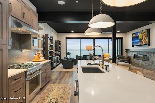 kitchen with open floor plan, a sink, high end stove, and under cabinet range hood