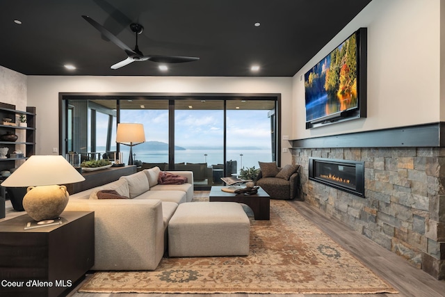 living room with a ceiling fan, a fireplace, and wood finished floors