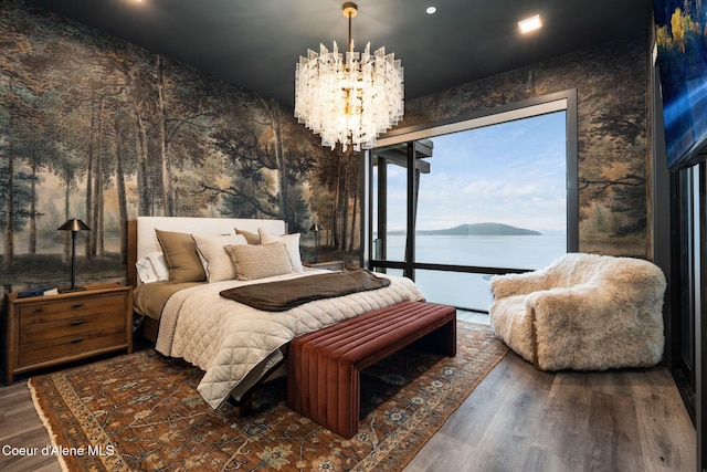 bedroom with access to outside, a water view, a notable chandelier, and wood finished floors