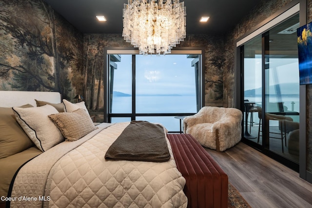 bedroom with an inviting chandelier, wood-type flooring, multiple windows, and access to outside