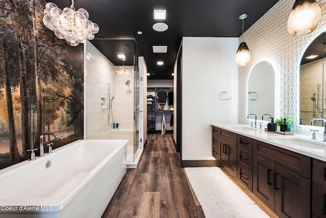 full bathroom featuring wood finished floors, a stall shower, a freestanding tub, and a sink