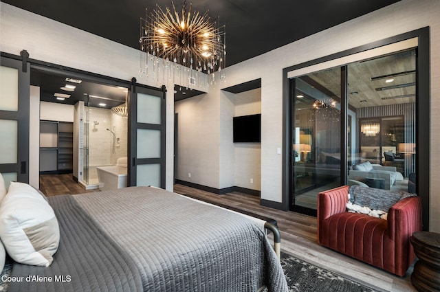 bedroom with access to outside, wood finished floors, a notable chandelier, and a barn door