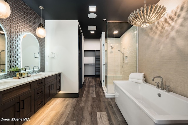 full bath with a freestanding tub, a shower stall, a sink, and wood finished floors