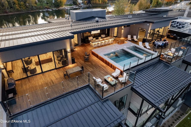 view of swimming pool with a water view, a community hot tub, and an outdoor living space with a fire pit