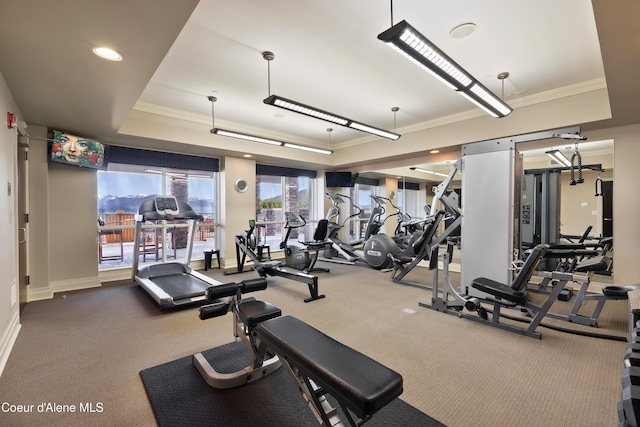 gym featuring baseboards, a raised ceiling, and crown molding
