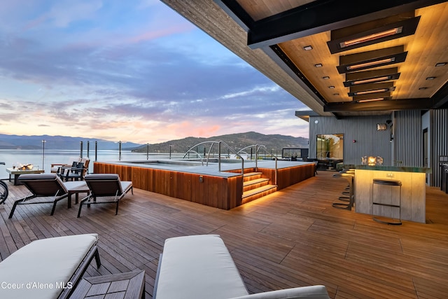 deck at dusk featuring a mountain view and a jacuzzi