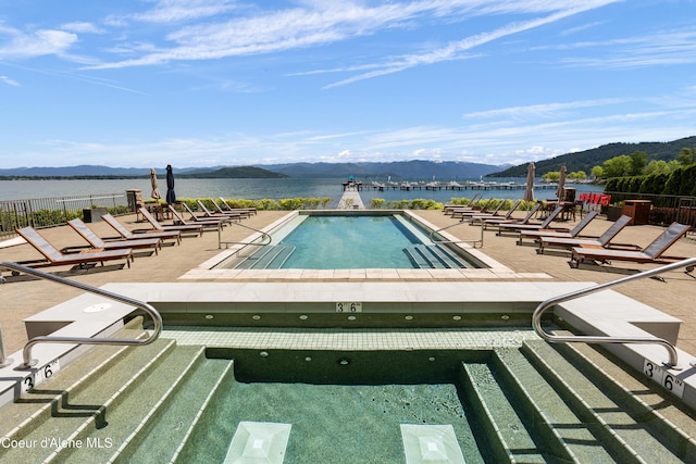 pool featuring fence, a water and mountain view, and a patio