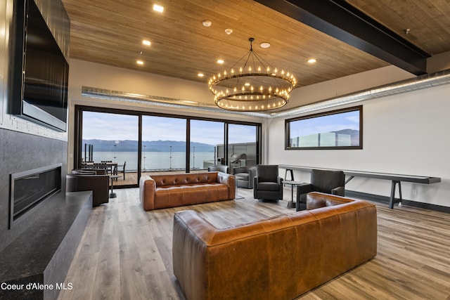 living area featuring a glass covered fireplace, wooden ceiling, wood finished floors, a chandelier, and a wealth of natural light