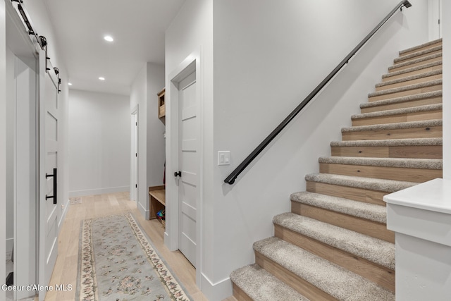 stairs with a barn door and wood-type flooring