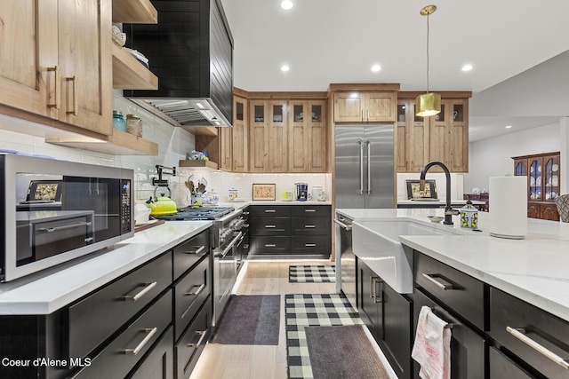 kitchen featuring premium appliances, light stone counters, decorative light fixtures, and light hardwood / wood-style flooring