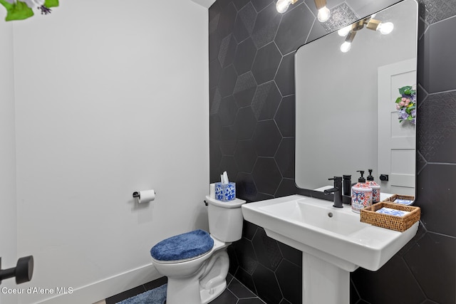 bathroom with tile patterned flooring, toilet, and tile walls