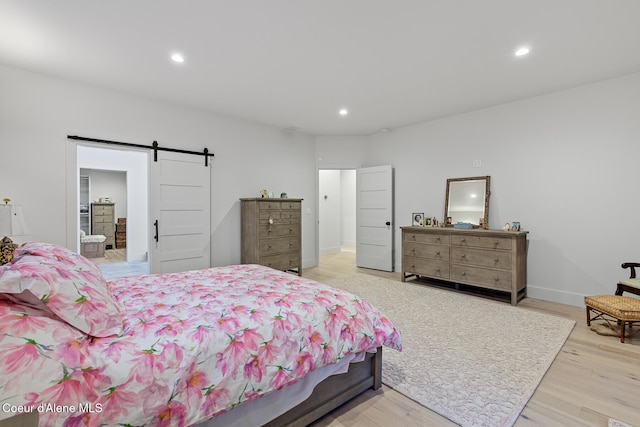 bedroom featuring a barn door and light hardwood / wood-style flooring