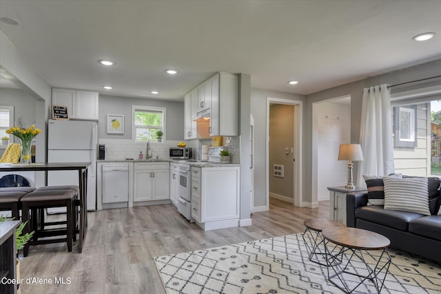 kitchen with sink, white appliances, decorative backsplash, white cabinets, and light wood-type flooring