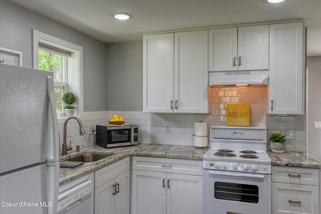 kitchen featuring white cabinetry, sink, light stone countertops, and white appliances