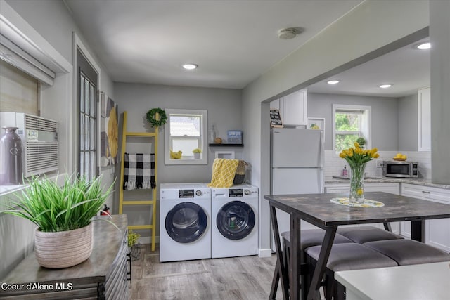 laundry area featuring washer and clothes dryer, plenty of natural light, and light hardwood / wood-style flooring