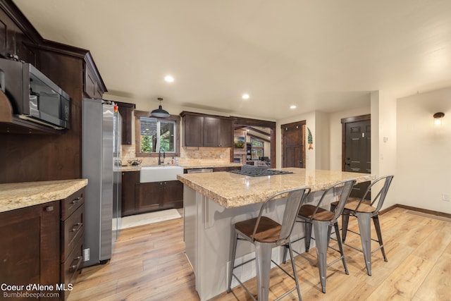 kitchen with sink, a kitchen island, plenty of natural light, and light wood-type flooring