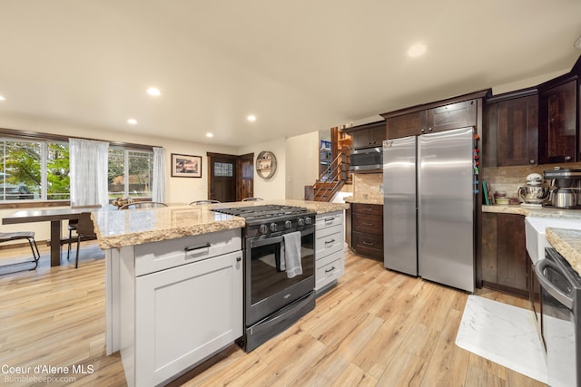 kitchen featuring dark brown cabinetry, stainless steel appliances, light hardwood / wood-style flooring, backsplash, and white cabinets