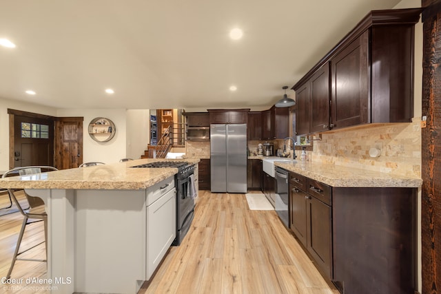 kitchen with sink, a center island, a kitchen breakfast bar, light hardwood / wood-style flooring, and appliances with stainless steel finishes