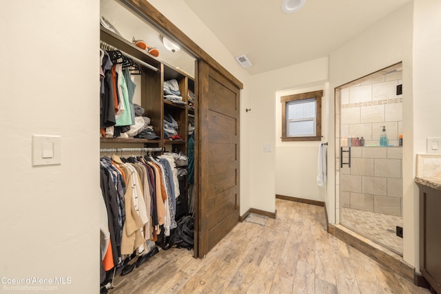 walk in closet with light hardwood / wood-style flooring