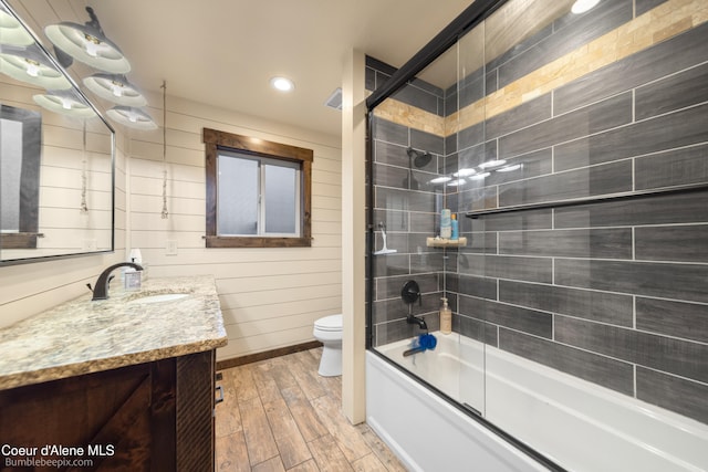 full bathroom with shower / bath combination with glass door, toilet, vanity, and hardwood / wood-style flooring