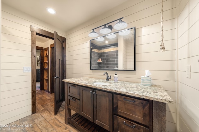 bathroom with wood-type flooring, vanity, and wood walls