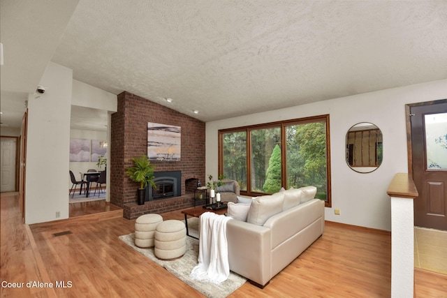 694 S Signal Point Rd, Post Falls, ID 83854 - living area featuring a textured ceiling, wood finished floors, vaulted ceiling, and a fireplace