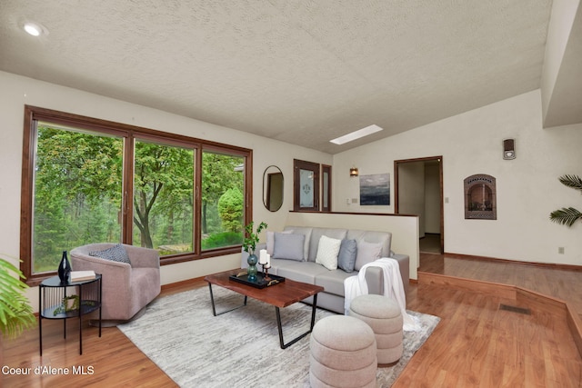 694 S Signal Point Rd, Post Falls, ID 83854 - living room featuring wood finished floors, lofted ceiling, plenty of natural light, a textured ceiling, and a skylight