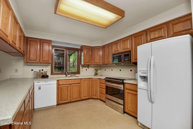 694 S Signal Point Rd, Post Falls, ID 83854 - kitchen with white appliances, light countertops, backsplash, and brown cabinets