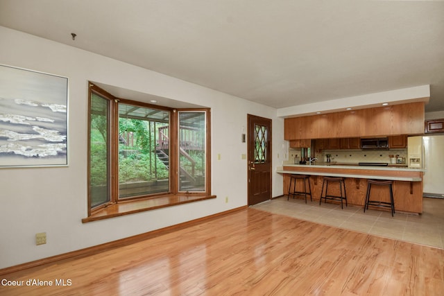 694 S Signal Point Rd, Post Falls, ID 83854 - kitchen featuring white refrigerator with ice dispenser, stainless steel microwave, light countertops, light wood-style floors, and decorative backsplash