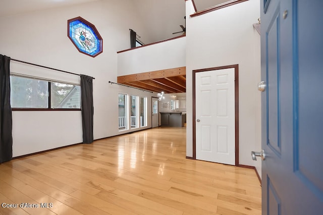 entryway with ceiling fan, high vaulted ceiling, and light hardwood / wood-style flooring