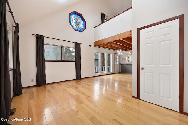 unfurnished room with beamed ceiling, light wood-type flooring, and high vaulted ceiling