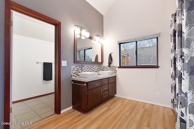 bathroom featuring hardwood / wood-style floors, vanity, tasteful backsplash, and vaulted ceiling