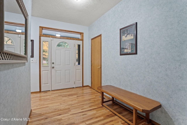 entrance foyer featuring a textured ceiling, light wood-type flooring, and a wealth of natural light