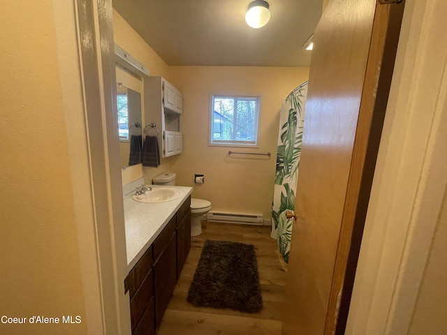 bathroom featuring vanity, hardwood / wood-style flooring, toilet, and a baseboard heating unit