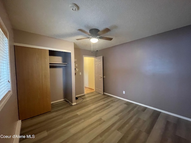 unfurnished bedroom with ceiling fan, a closet, a textured ceiling, and hardwood / wood-style flooring