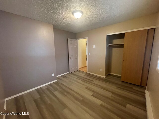 unfurnished bedroom with hardwood / wood-style floors, a textured ceiling, and a closet